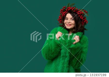 Smiling woman in green coat and red berry wreath posing. Smiling woman in green coat and red berry wreath posing. 131937199