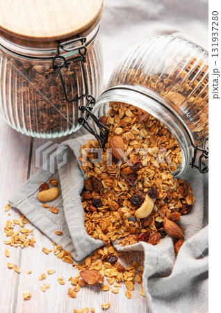 Granola mix with oats, nuts, and dried fruits spilling onto a grey napkin Granola mix with oats, nuts, and dried fruits spilling onto a grey napkin 131937280