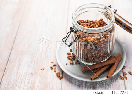 Granola cereal in glass jar with cinnamon sticks 131937281