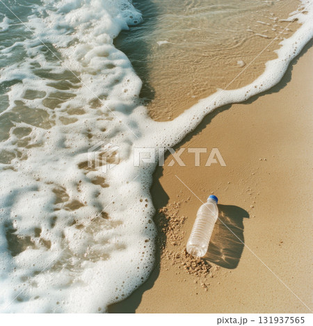 Waves washing over a plastic bottle on the sandy beach at sunset 131937565