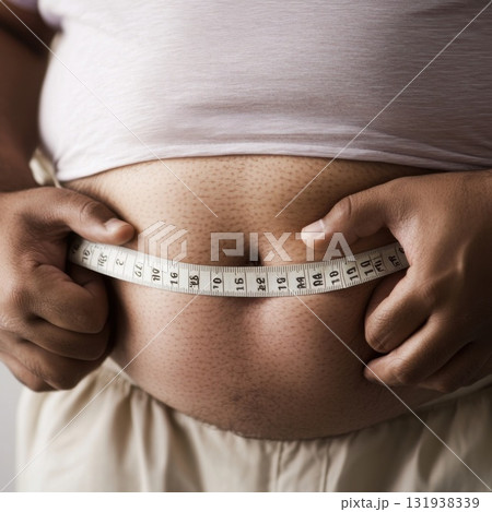 Man measuring waist with tape measure while assessing body size in a casual indoor setting 131938339