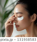 Woman applying eye patches in a serene indoor setting surrounded by greenery for self-care and relaxation 131938583