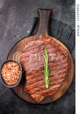 Grilled Flank Flap beef steak, showcasing beautiful grill marks. black background. top view Grilled Flank Flap beef steak, showcasing beautiful grill marks. black background. top view 131939932