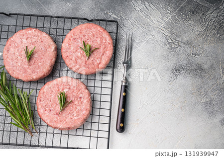 Close up of a juicy raw meat patty cutlet, ideal for crafting mouthwatering sandwiches and savory dishes. white background. top view Close up of a juicy raw meat patty cutlet, ideal for crafting mouthwatering sandwiches and savory dishes. white background. top view 131939947