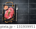 Marbled raw Rib eye steak with herbs in wooden tray, fresh beef meat. black kitchen background. top view 131939951