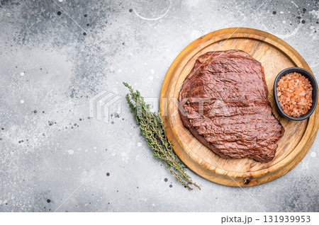 Perfectly grilled top sirloin steak, seared to a juicy finish and garnished with fresh herbs for an irresistible flavor. grey background. top view Perfectly grilled top sirloin steak, seared to a juicy finish and garnished with fresh herbs for an irresistible flavor. grey background. top view 131939953