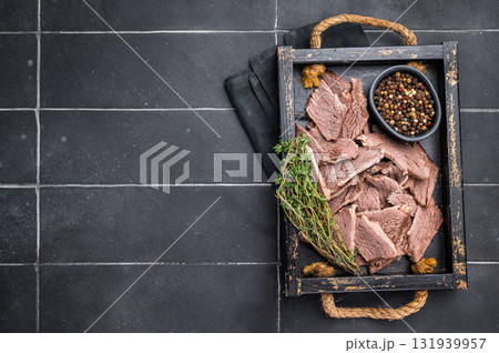 Cooked boiled sliced beef meat in wooden tray. black background. top view Cooked boiled sliced beef meat in wooden tray. black background. top view 131939957