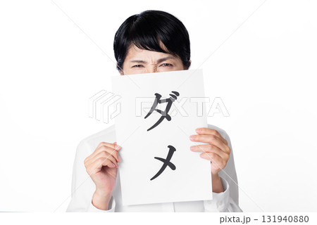 ダメと書かれた紙を持ち眉間にシワを寄せるシニア女性 131940880