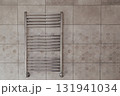 A chrome towel warmer on a tiled wall in a bathroom. 131941034