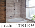 Corner acrylic bathtub with plastic front panel underneath in a bathroom with a window. 131941036