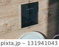 Close-up of a chrome dual flush button on a wall with wood-grain tiles 131941043