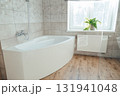Corner acrylic bathtub with plastic front panel underneath in a bathroom with a window 131941048