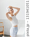 Cheerful attractive woman with a towel wrapped around her head posing in bathroom 131941051