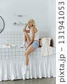 Young woman sitting on a tabletop made of tiles in bathroom 131941053