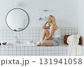 Young woman sitting on a tabletop made of tiles in bathroom 131941058