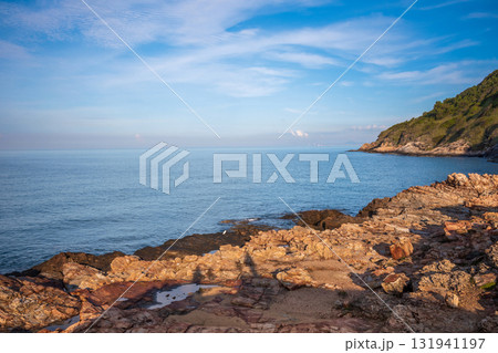 Beautiful seascape at Khao Laem Ya in Rayong, Thailand, featuring golden-brown rocks along the shoreline and lush green cliffs under a clear blue sky 131941197