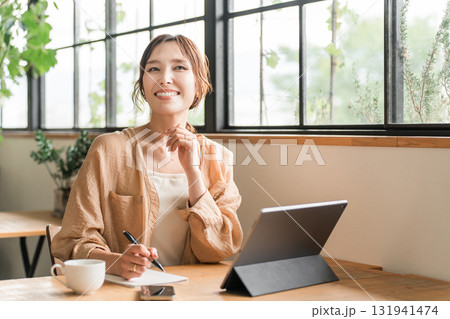 カフェでコーヒーを飲みながらをしながらノマドワークをする女性 カフェでコーヒーを飲みながらをしながらノマドワークをする女性 131941474