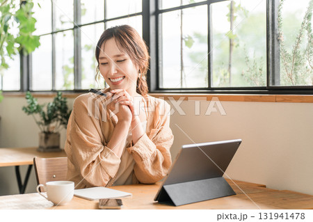 カフェでコーヒーを飲みながらをしながらノマドワークをする女性 カフェでコーヒーを飲みながらをしながらノマドワークをする女性 131941478