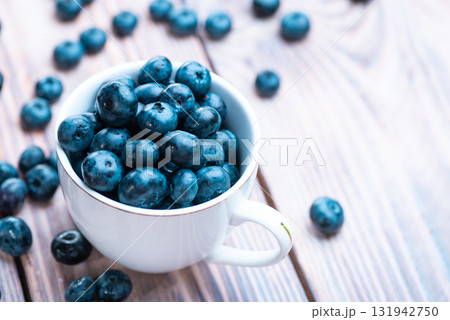 Fresh blueberries in a white cup on a wooden table Fresh blueberries in a white cup on a wooden table 131942750