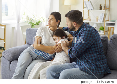 Worried parents comforting sad child on couch during family crisis at home Worried parents comforting sad child on couch during family crisis at home 131943676