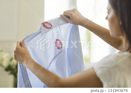Woman stressed holding shirt with lipstick kiss marks symbolizing cheating and divorce Woman stressed holding shirt with lipstick kiss marks symbolizing cheating and divorce 131943678
