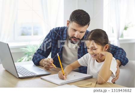 Caring father tutoring daughter on homework beside laptop in bright cozy home 131943682