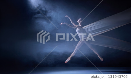 Ballet dancer entangled in fabric mid-motion on dark stage with spotlight Ballet dancer entangled in fabric mid-motion on dark stage with spotlight 131943703
