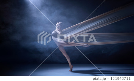 Ballet dancer entangled in fabric performing balance move under spotlight Ballet dancer entangled in fabric performing balance move under spotlight 131943711