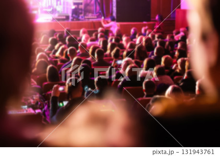 a large audience crowd seated in a majestic theater, theatre, auditorium. the people blurred to highlight the stage or screen for a show, concert, or film festival 131943761