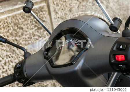 A close-up view of a motorcycle scooters speedometer and handlebars A close-up view of a motorcycle scooters speedometer and handlebars 131945003