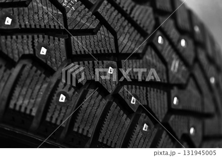A brand new black studded car tire with metal studs embedded within the tread 131945005