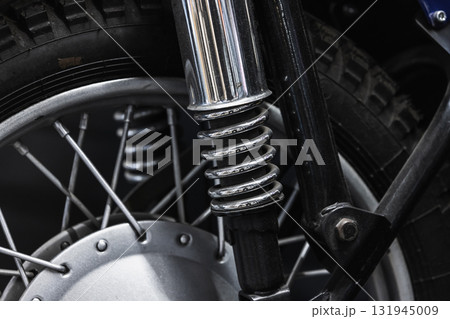 A detailed close-up of a motorcycle front suspension featuring a chrome coil spring 131945009