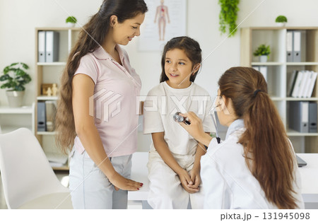 Pediatrician examining child with mother during clinic checkup using stethoscope 131945098