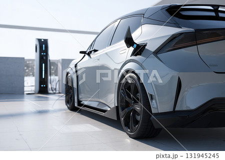 A close-up of an electric car approaching a charging station during the day. 131945245