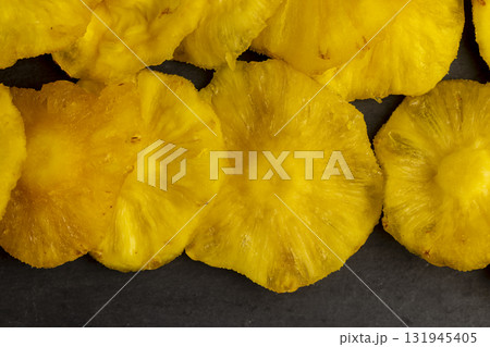 dried ripe bright yellow pineapple on a black slate board, cut into rings and dried yellow clean slices of ripe pineapple for long-term storage and used as a sweet 131945405