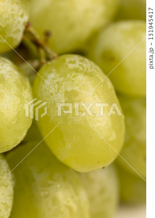 a branch of ripe beautiful green grapes lying on the table, covered with water, wet fruits of pure green grapes on a branch on the table during cooking 131945417