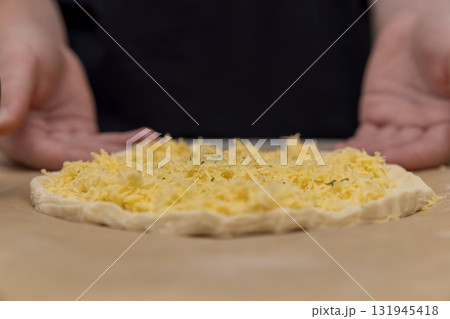 cheese tortilla made of yeast dough and grated cheese, thinly yeast dough sprinkled with yellow hard grated cheese 131945418