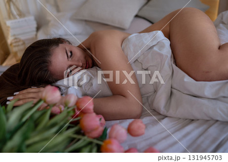 Woman sleeping bed, woman sleeping comfortably in a white bed surrounded by pink tulips, conveying peaceful morning relaxation 131945703