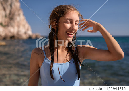Teenager, beach, summer, happy young woman enjoying a sunny day by the ocean with wet hair 131945713