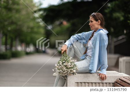 Woman Flowers Park: Pensive woman with daisies relaxes in park, summer day, enjoying the beauty of nature. 131945790