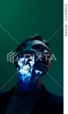 Man with glowing botanical projection on neck looking aside under dark moody lighting 131946052