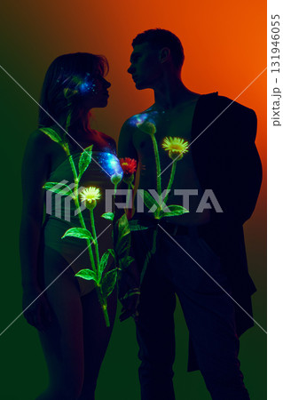 Couple standing under glowing floral light projection on bodies with dark background Couple standing under glowing floral light projection on bodies with dark background 131946055