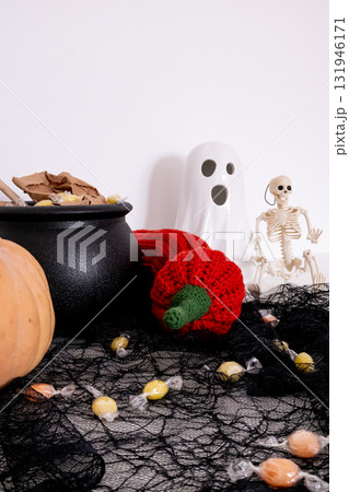 Halloween decor with ghost figurine, candy, and skeleton on black netting 131946171