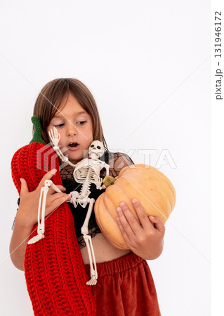 Young caucasian girl holding knitted pumpkin and Halloween skeleton with copy space for text 131946172