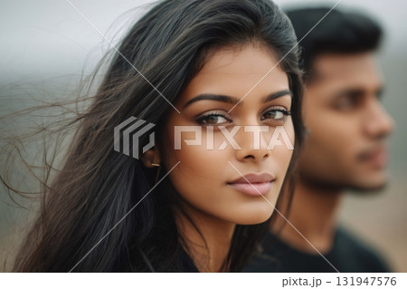 Indian woman looking at camera with man behind 131947576