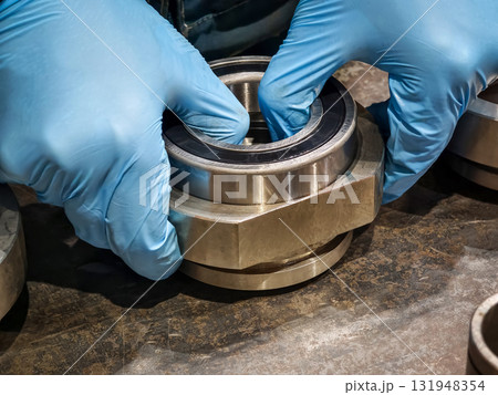 Hands assembling metal components in a workshop with focus on precision and craftsmanship 131948354