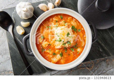 Spanish zurrukutuna soup with bread, garlic, cod and eggs close-up in a saucepan. Horizontal top view 131948613