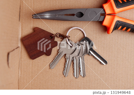 Door keys with wooden house-shaped keychain and construction tool in cardboard delivery box Door keys with wooden house-shaped keychain and construction tool in cardboard delivery box 131949648