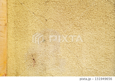 Ancient yellow painted rough wall with weathered uneven texture 131949656