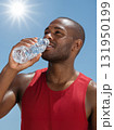 Thirsty athletic man drinking water to cool down on a hot sunny day. 131950199